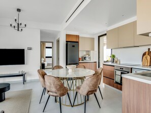 Une cuisine moderne dotée d’un îlot central, d’appareils électroménagers intégrés et d’un coin repas avec une table ronde et des chaises.