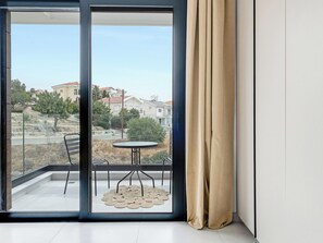 A balcony with a table and chairs, a view of a residential area, and a curtain on the right. - Sanders Elgio Limassol - Full Building (Limassol)