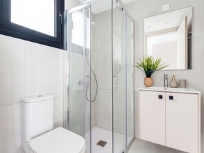 A modern bathroom with a glass shower enclosure, a toilet, a sink with a mirror, and a potted plant. - Sanders Elgio Limassol - Full Building (Limassol)