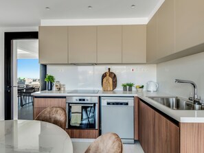 Eine moderne Küche mit Geschirrspüler, Backofen und Spüle. Auf der Arbeitsplatte liegen ein Holzschneidebrett und ein Blumentopf.
