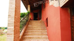 A staircase leading to a red building with a metal railing and a wooden door. - Amaranth House Rooms and Apartments (Bastia Umbra)