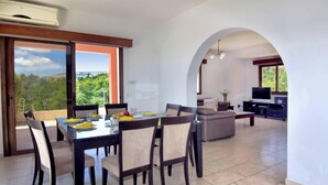 A dining area with a table and chairs, a living room with a sofa, and a kitchen area with a TV and cabinets. - Family Villa Short Walk To Coral Bay Strip 5 Min and Pub, Shops etc (Pegeia)