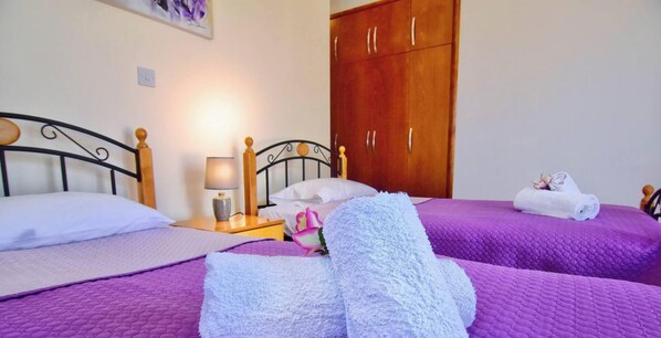 A double room with two beds, a wooden wardrobe, a nightstand with a lamp, and a wall-mounted light fixture. - Family Villa Short Walk To Coral Bay Strip 5 Min and Pub, Shops etc (Pegeia)