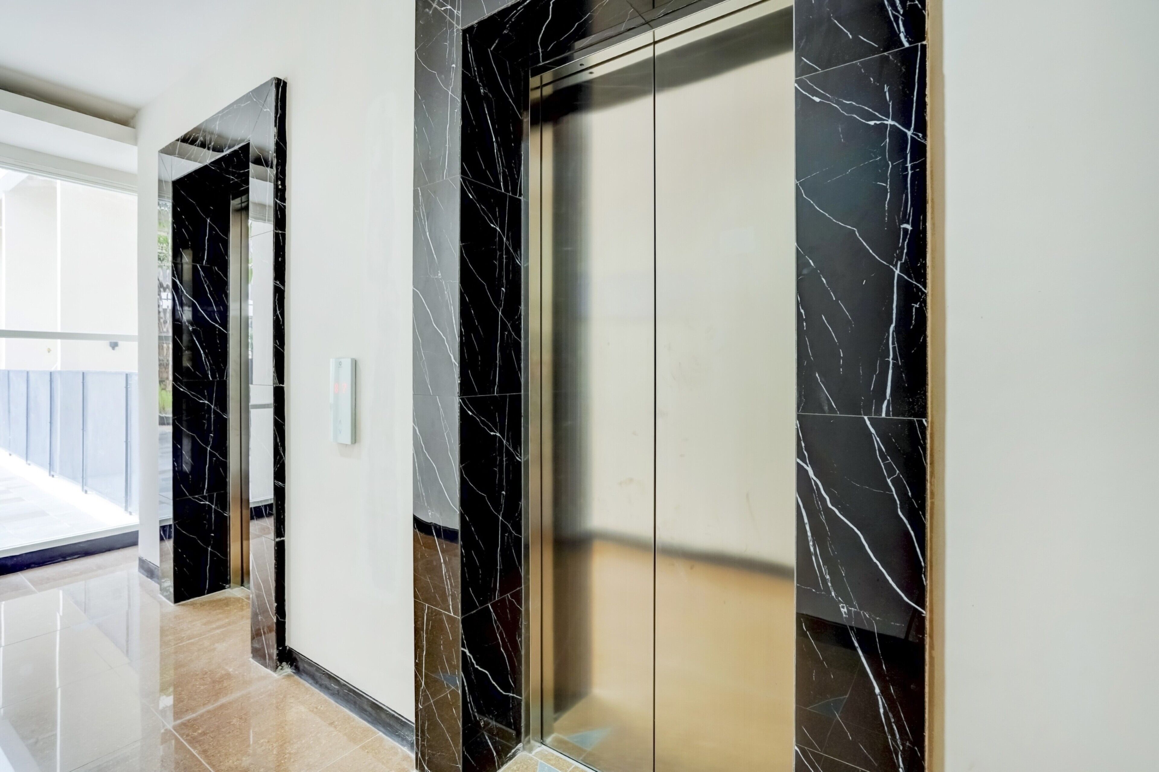 A modern elevator with black marble walls and a reflective floor.