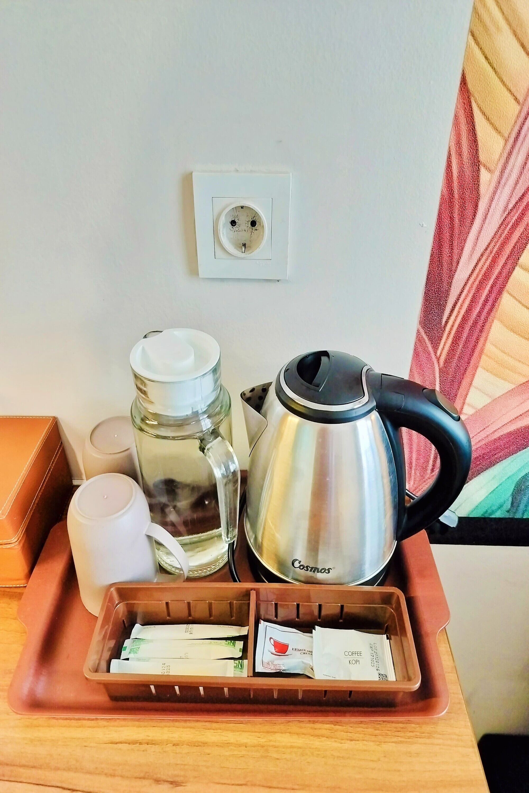 Ein Tablett mit einer Kaffeemaschine, einer Wasserflasche und einer Tasse auf einem Holztisch.