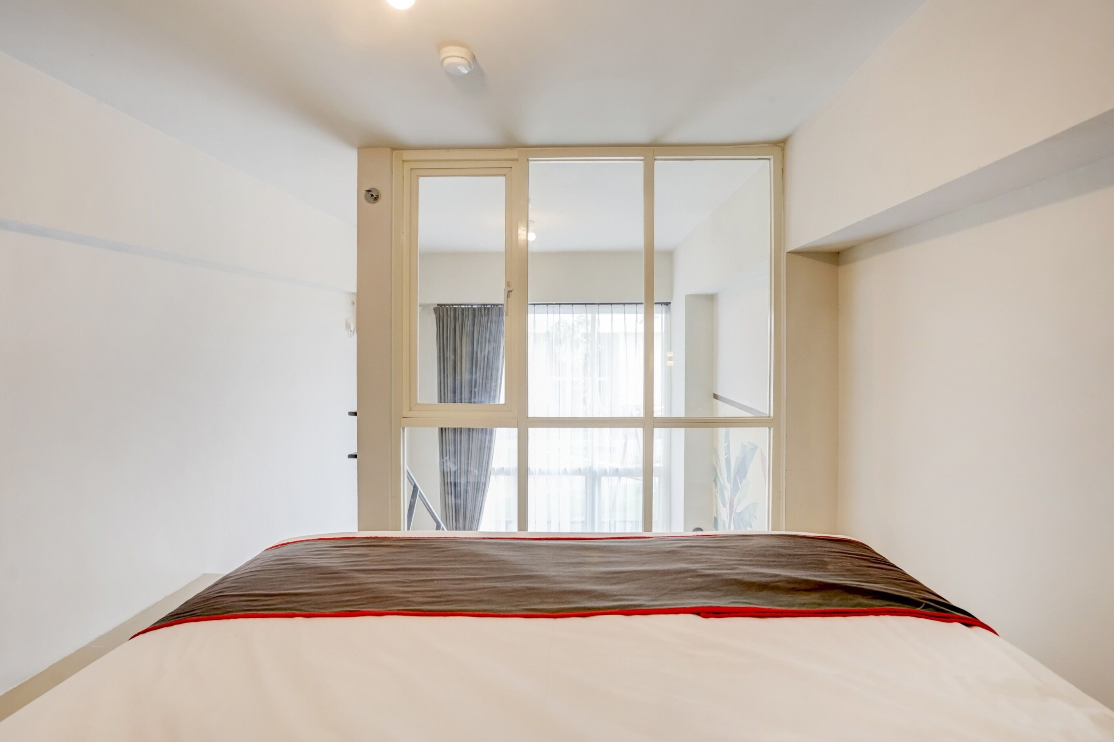 Ein Schlafzimmer mit Bett, Fenster und einer Tür zu einem anderen Raum.