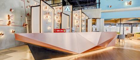 A modern reception desk with a geometric design, surrounded by walls adorned with butterfly decorations and a logo.