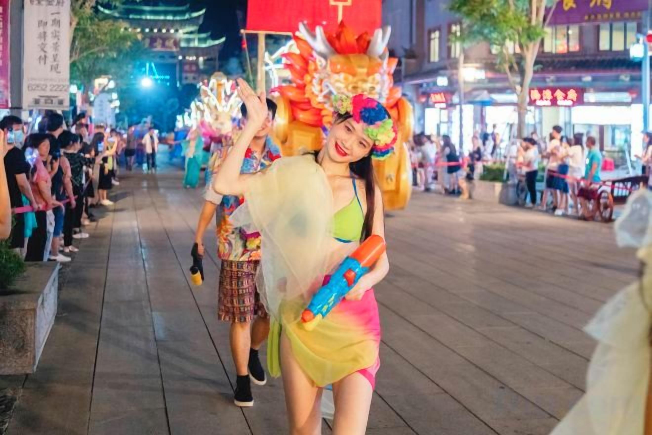 Uma pessoa vestida com um traje colorido caminhando em uma rua, com uma multidão ao fundo.
