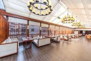Un vaste espace intérieur doté d’un plancher en bois, de plusieurs coins salon et de grands luminaires au plafond.