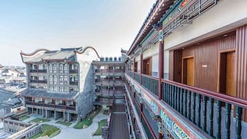 A multi-story hotel with traditional architectural elements, including a balcony with railings and a courtyard with a pathway.