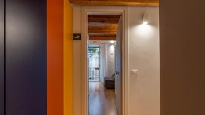 Un couloir avec un plafond en bois, une porte donnant sur une pièce et une vue sur un balcon doté d’une balustrade.