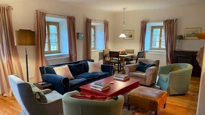 Ein Wohnzimmer mit einer Couch, Sesseln, einem Couchtisch und einem Essbereich mit Stühlen und einem Tisch.