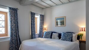 Ein Schlafzimmer mit einem großen Bett, gemusterten Vorhängen und zwei Nachttischlampen.