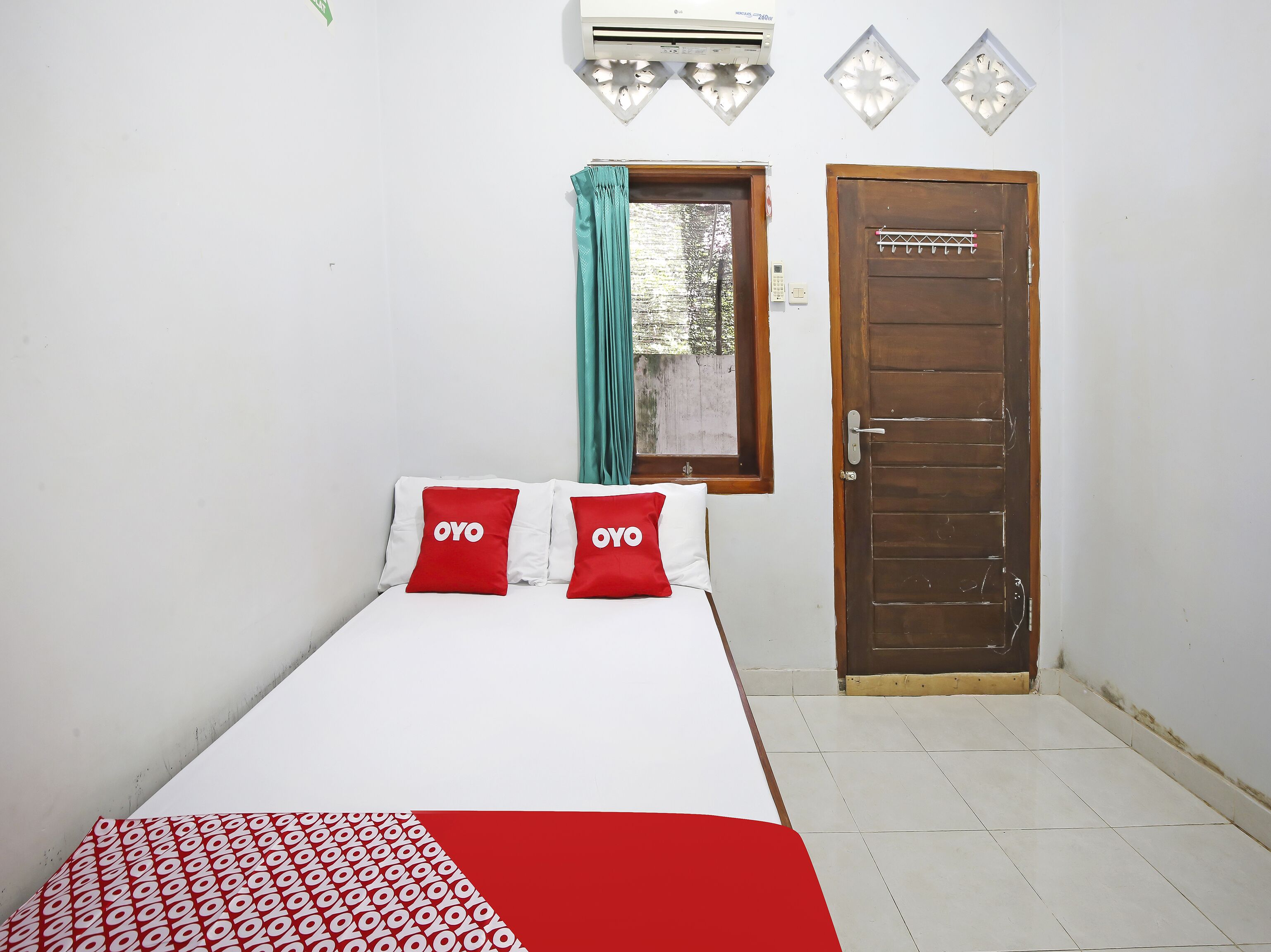 A hotel room with a bed, a window with curtains, a door, and an air conditioning unit.