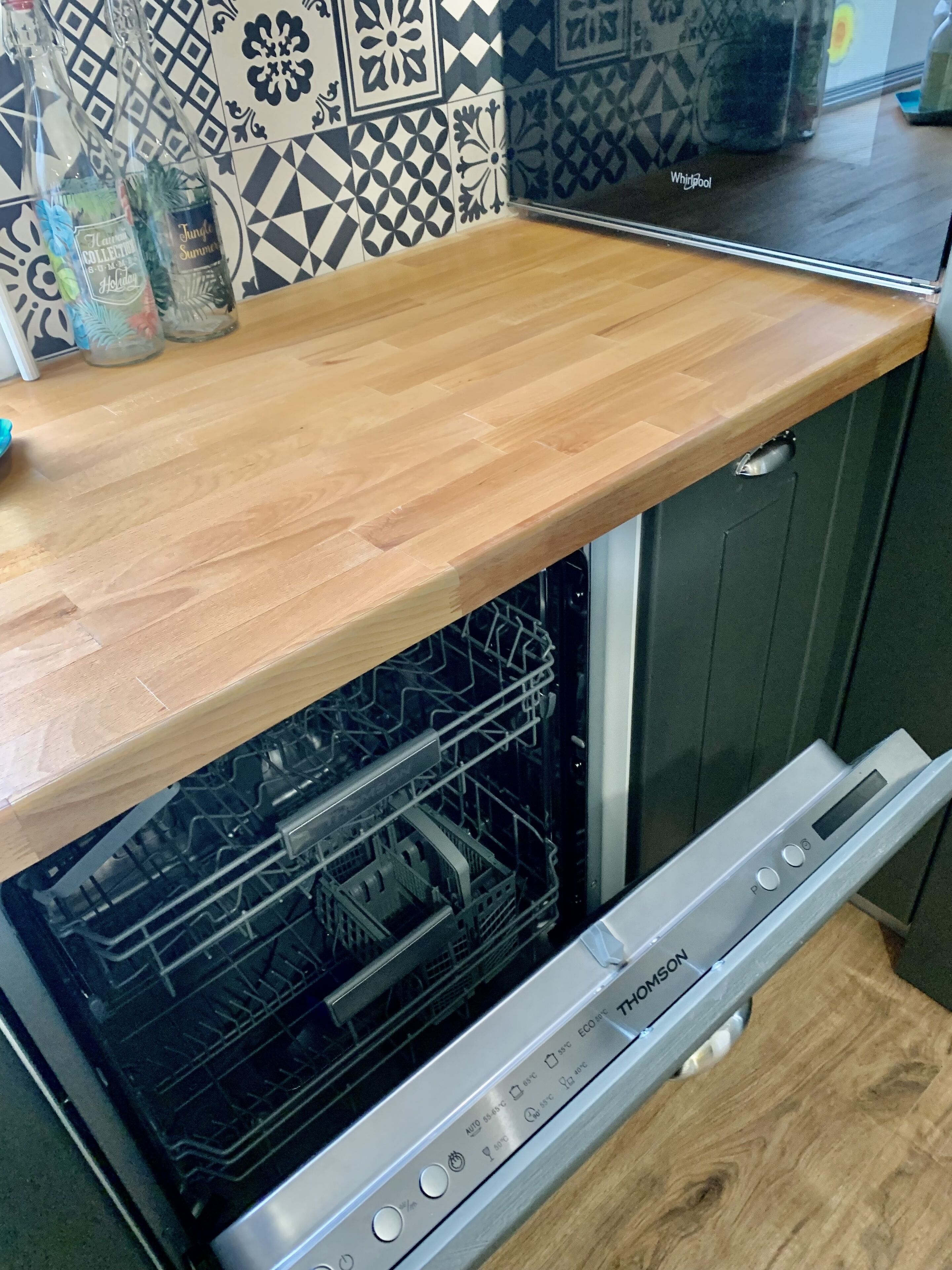 Une cuisine dotée d’un plan de travail en bois, d’un lave-vaisselle et d’un crédence décorée.