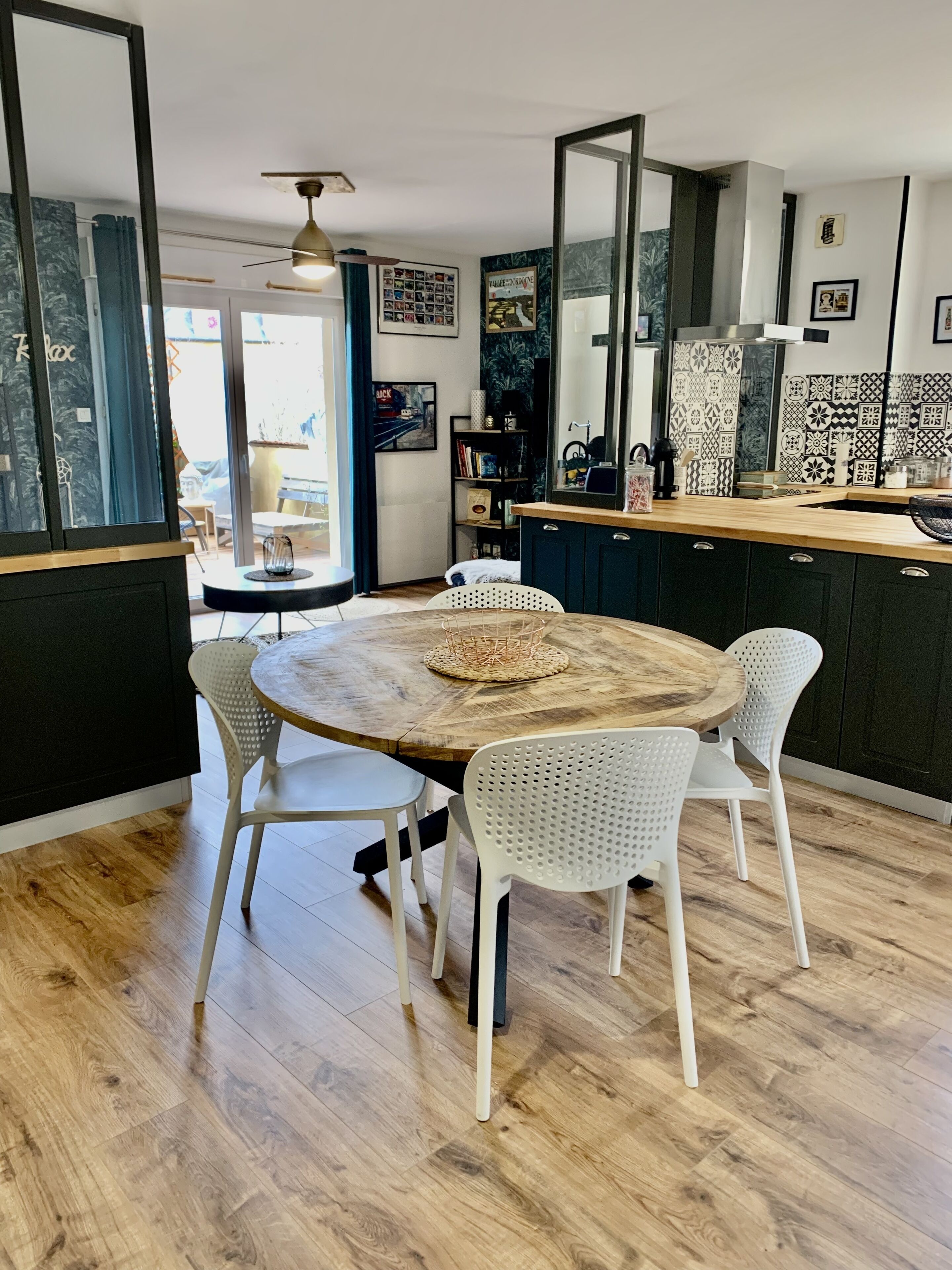 Een moderne keuken met een houten eettafel, witte stoelen en een grote spiegel.