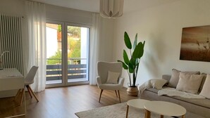 A modern living room with a sofa, a coffee table, a chair, and a large plant.