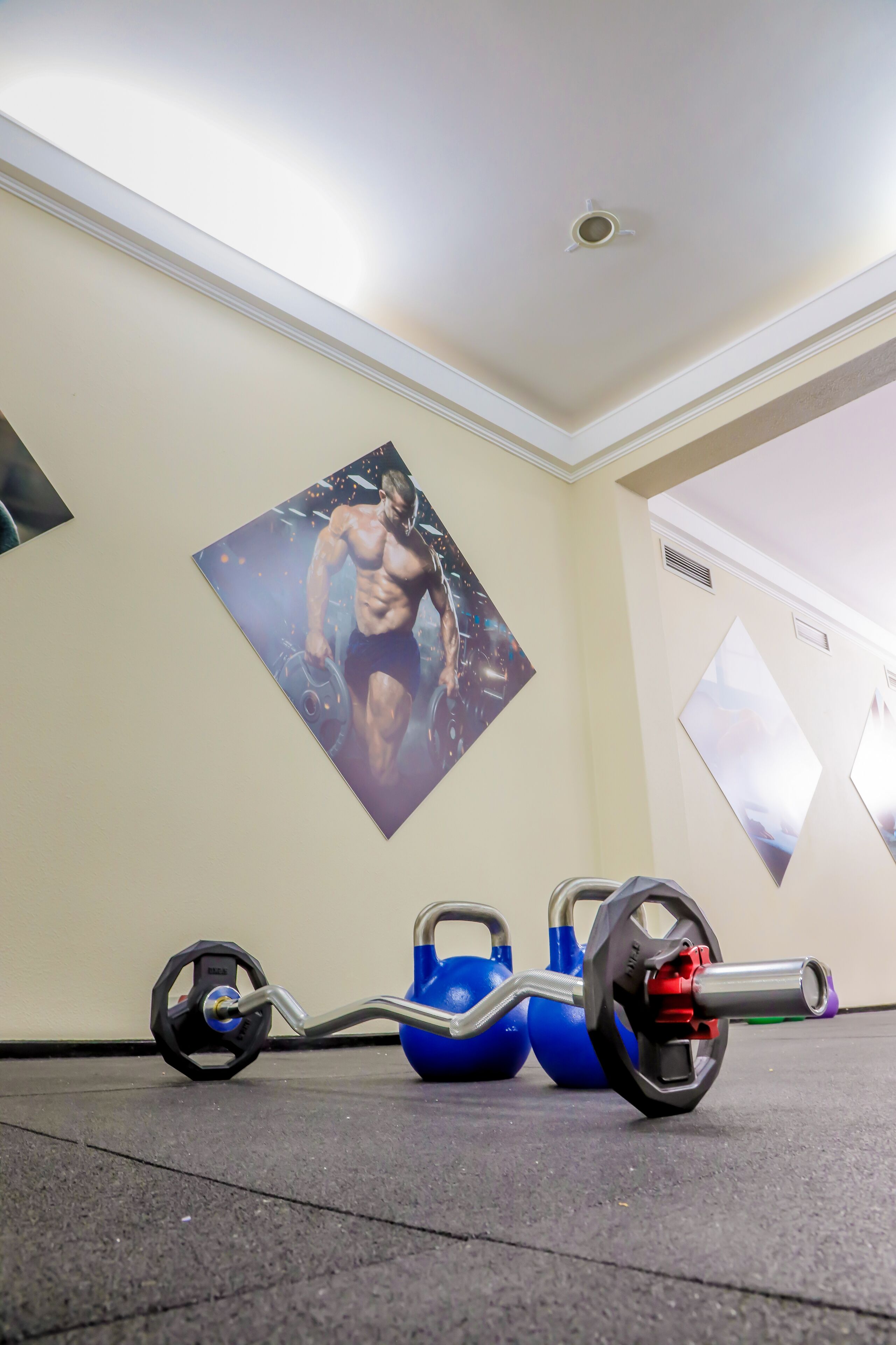 A gym with a weightlifting bench, kettlebells, and barbells.