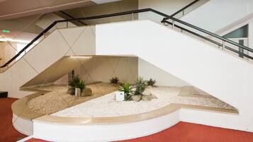 A modern interior with a curved staircase, a small indoor garden, and a red carpeted floor.