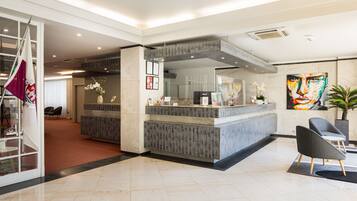 A modern reception area with a marble floor, a reception desk, and a large abstract painting.