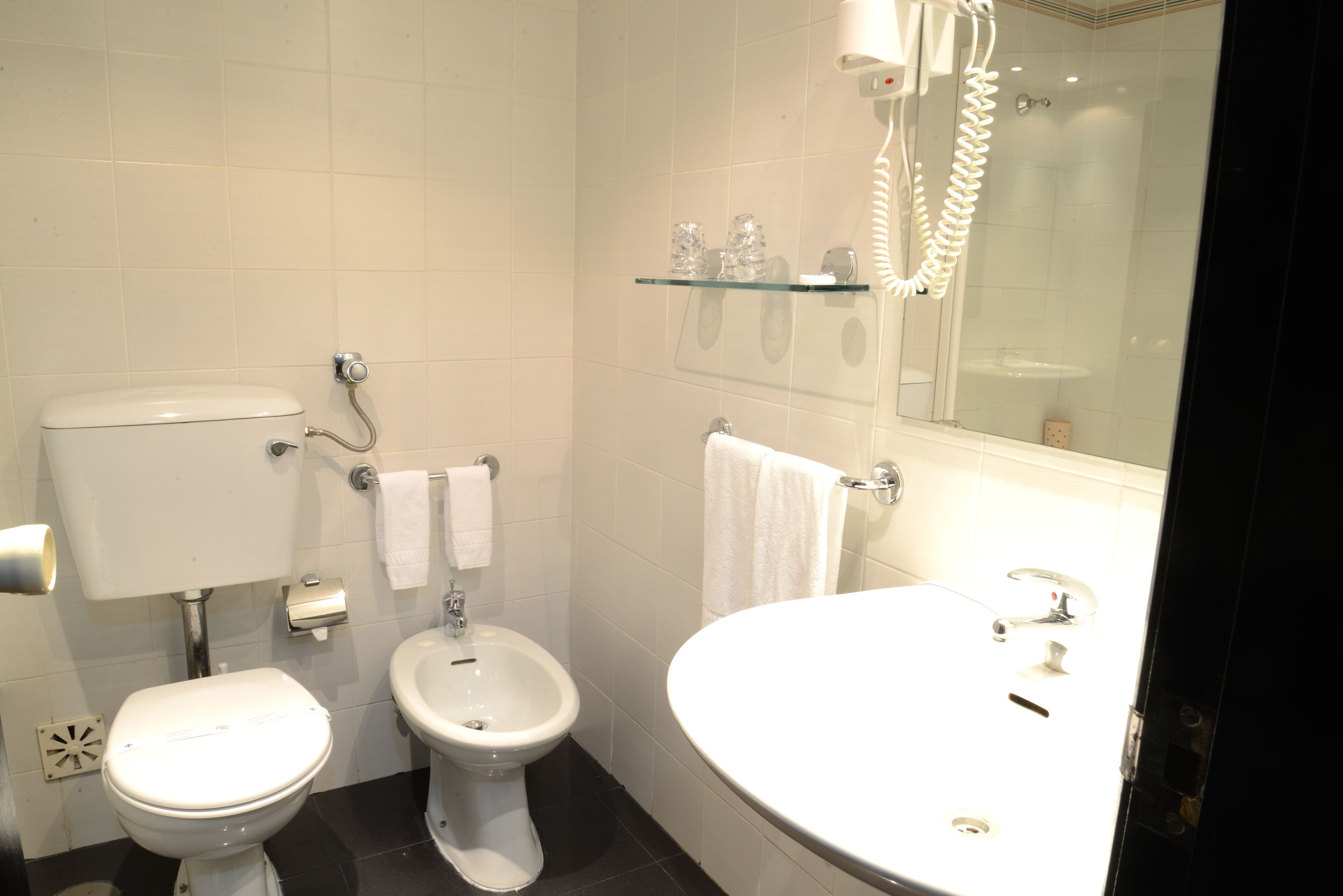 A bathroom with a toilet, bidet, and a large sink.