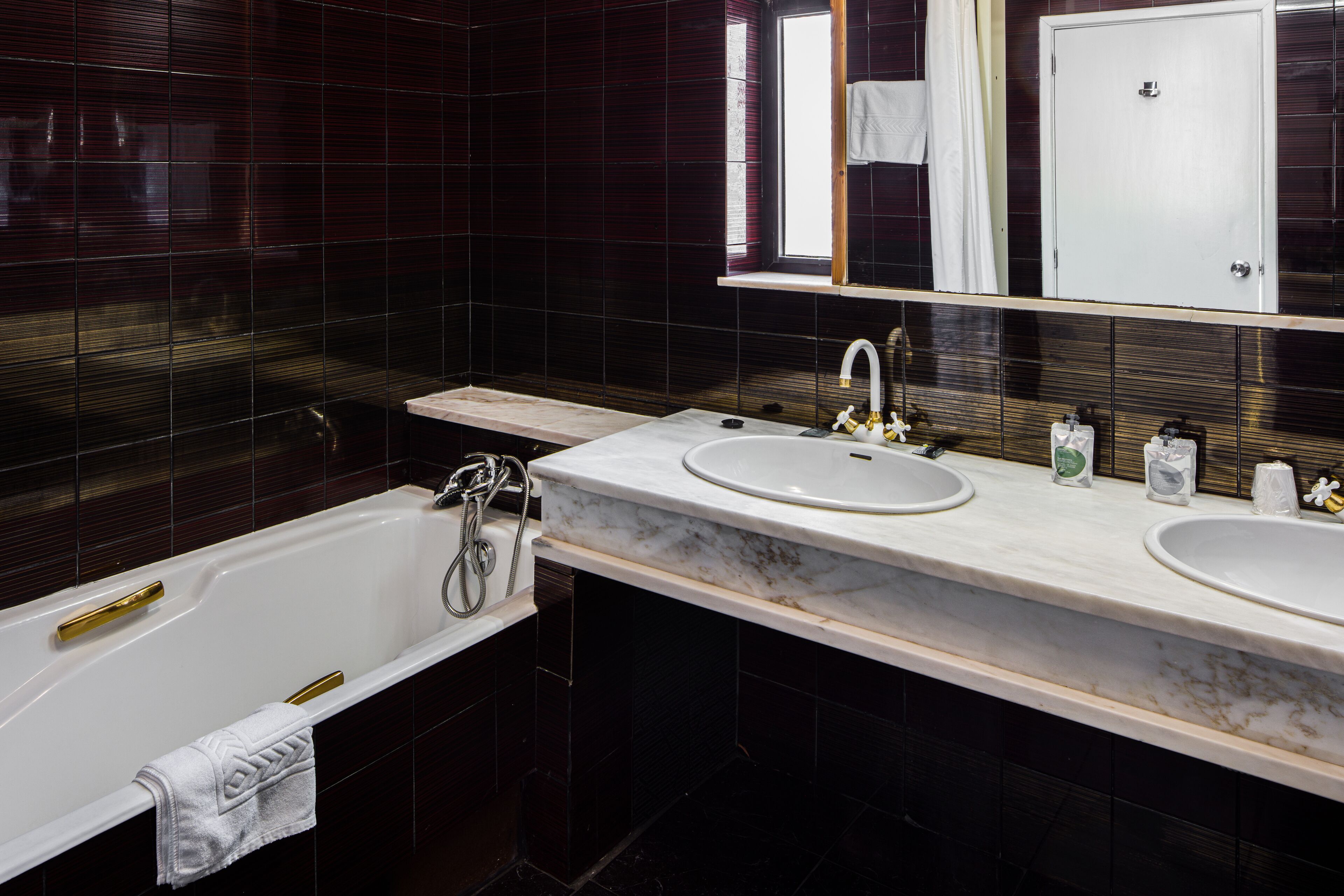 Un baño moderno con bañera, dos lavamanos y un espejo grande.