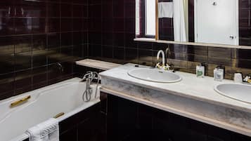 Un baño moderno con bañera, dos lavamanos y un espejo grande.