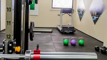 A gym with weightlifting equipment, treadmills, and kettlebells.