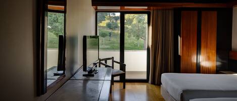 A hotel room with a large window, a desk with a chair, and two beds.