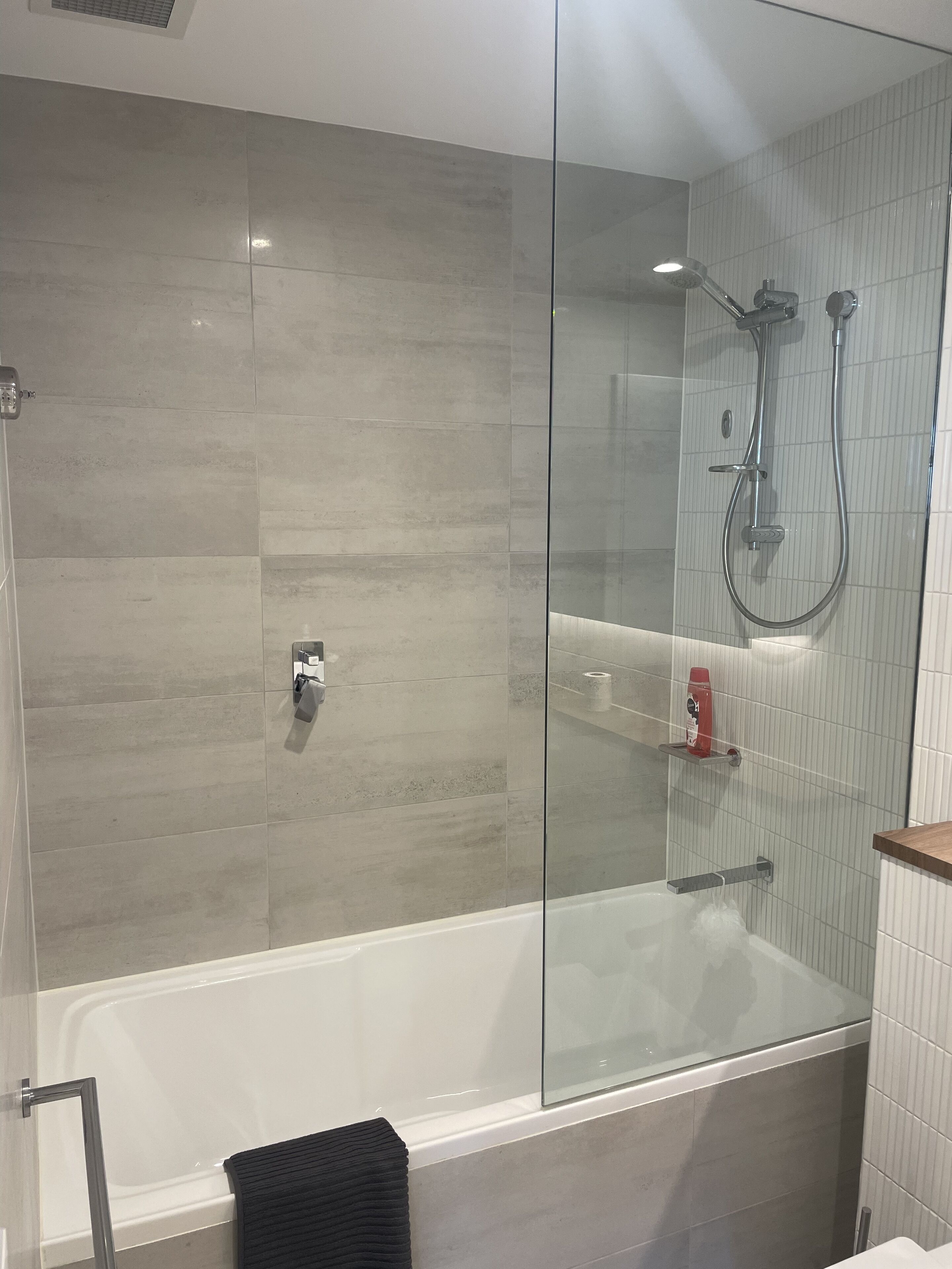 Et moderne badeværelse med en glasafskærmet brusekabine, badekar og toilet.