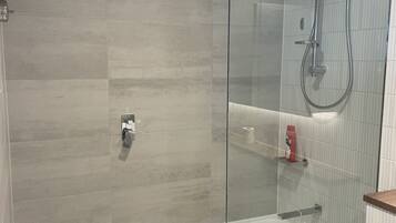 Et moderne badeværelse med en glasafskærmet brusekabine, badekar og toilet.