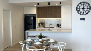 Una cocina moderna con una isla central, muebles blancos y un refrigerador negro.