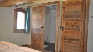 Ein Schlafzimmer mit einem großen Bett, einem Holzschrank und einem Badezimmer mit Dusche und Toilette.
