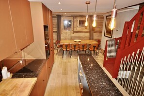A modern kitchen with a wooden dining table, built-in cabinets, and a red staircase.