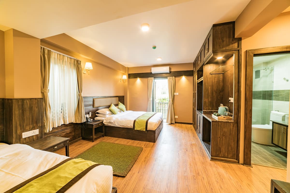 A hotel room with a bed, bedside table, lamp, and a view of the outside.