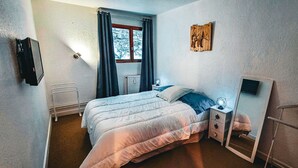 A bedroom with a bed, bedside table, nightstand, and a mirror.