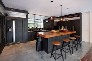 A modern kitchen with a large island, bar stools, and pendant lighting.
