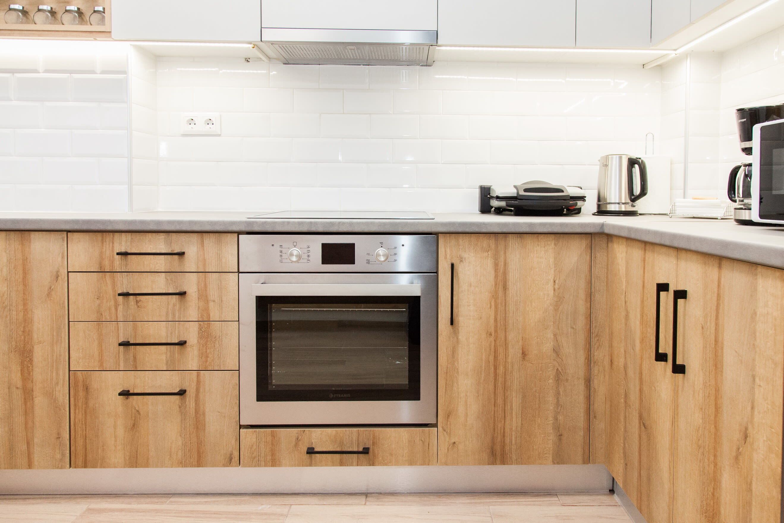 Una cucina moderna con mobili in legno, elettrodomestici in acciaio inossidabile e piastrelle bianche a metro.