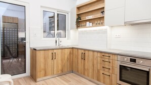 Une cuisine moderne avec des meubles en bois, un four encastré et une fenêtre au-dessus de l’évier.
