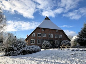 Ein traditionelles Fachwerkhäuschen mit steilem Dach und verschneiter Landschaft.