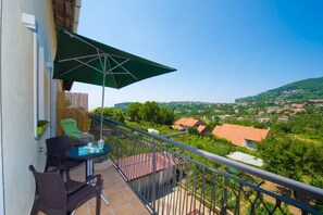 Ein Balkon mit Tisch, Stühlen und einem grünen Sonnenschirm.