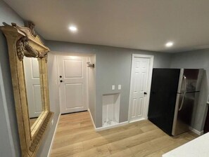 Compact kitchen with a large mirror, refrigerator, and warm-toned flooring.