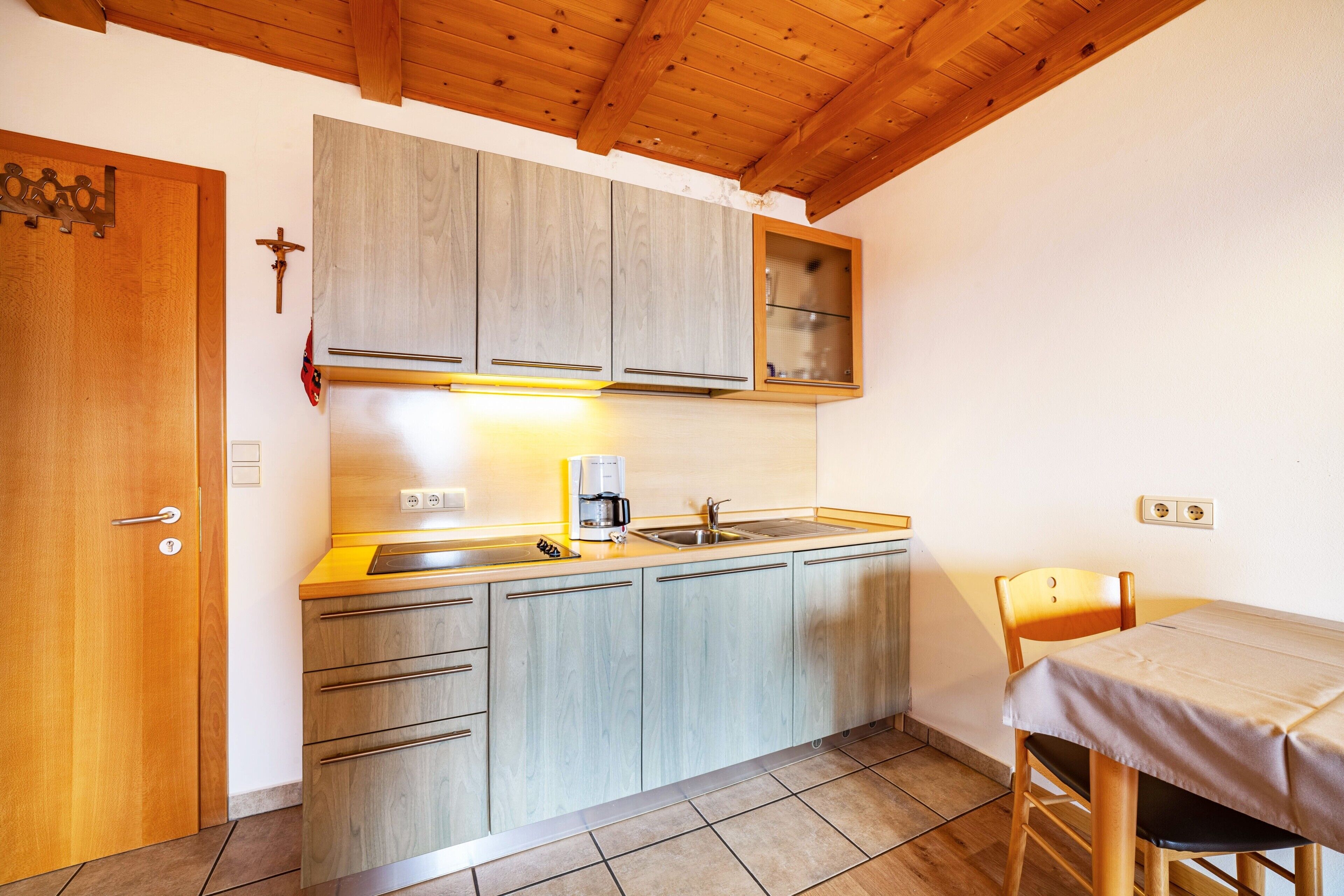 Eine kleine Küche mit Holzausstattung, einer Spüle und einem Essbereich mit Tisch und Stuhl.