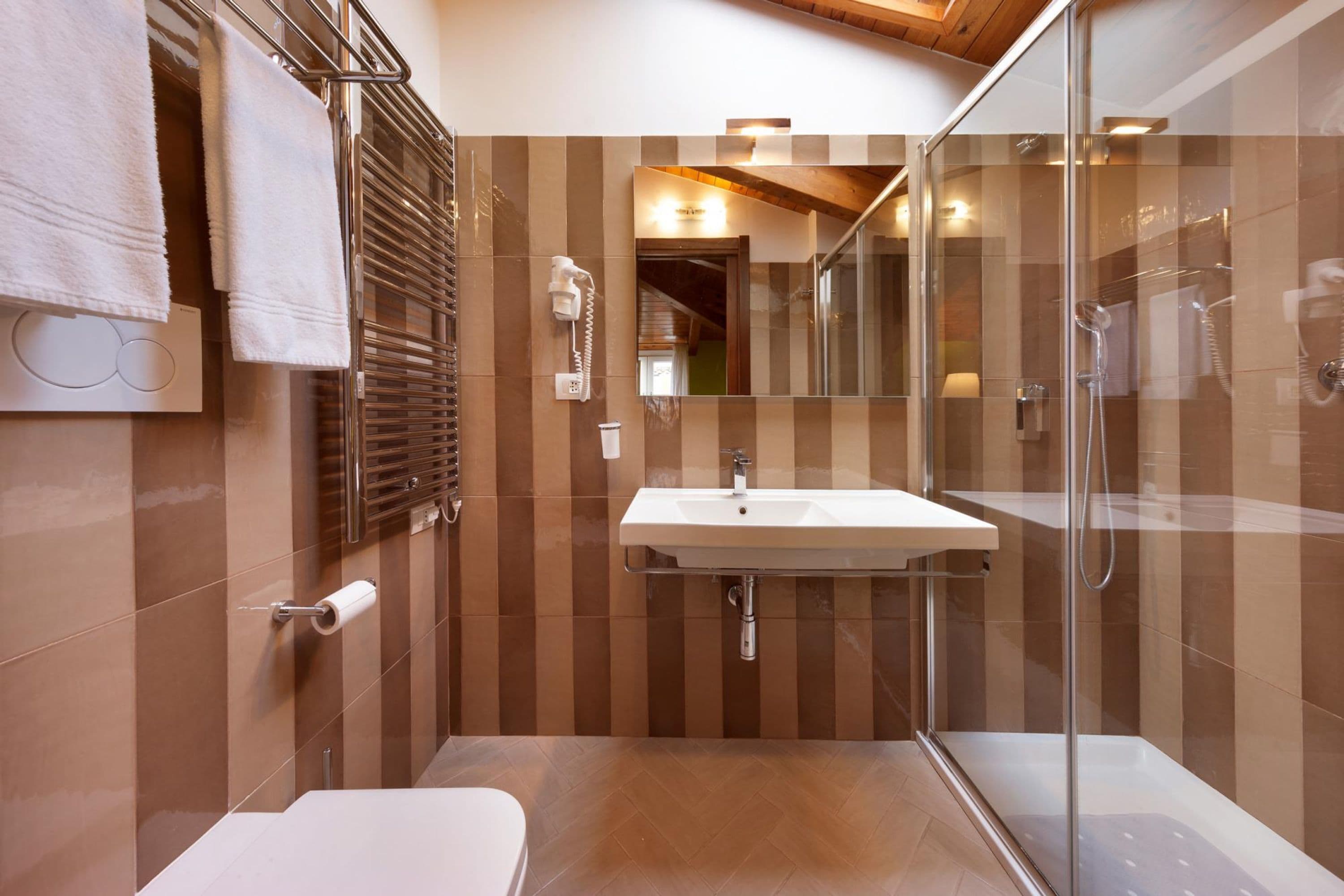 A modern bathroom with a glass shower enclosure, a white sink, and a toilet.