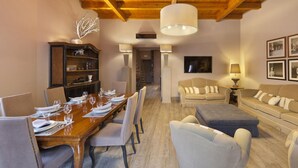 A dining area with a wooden table set for six, flanked by chairs, and a sofa with cushions. - Maison De Charme in Sorrento (Sorrento)