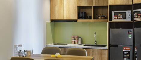 A modern kitchen with wooden cabinets, a stainless steel refrigerator, and a dining area with a table and chairs.