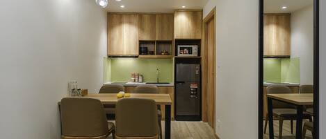 A compact kitchen with wooden cabinets, a black refrigerator, and a dining area with chairs and a table.