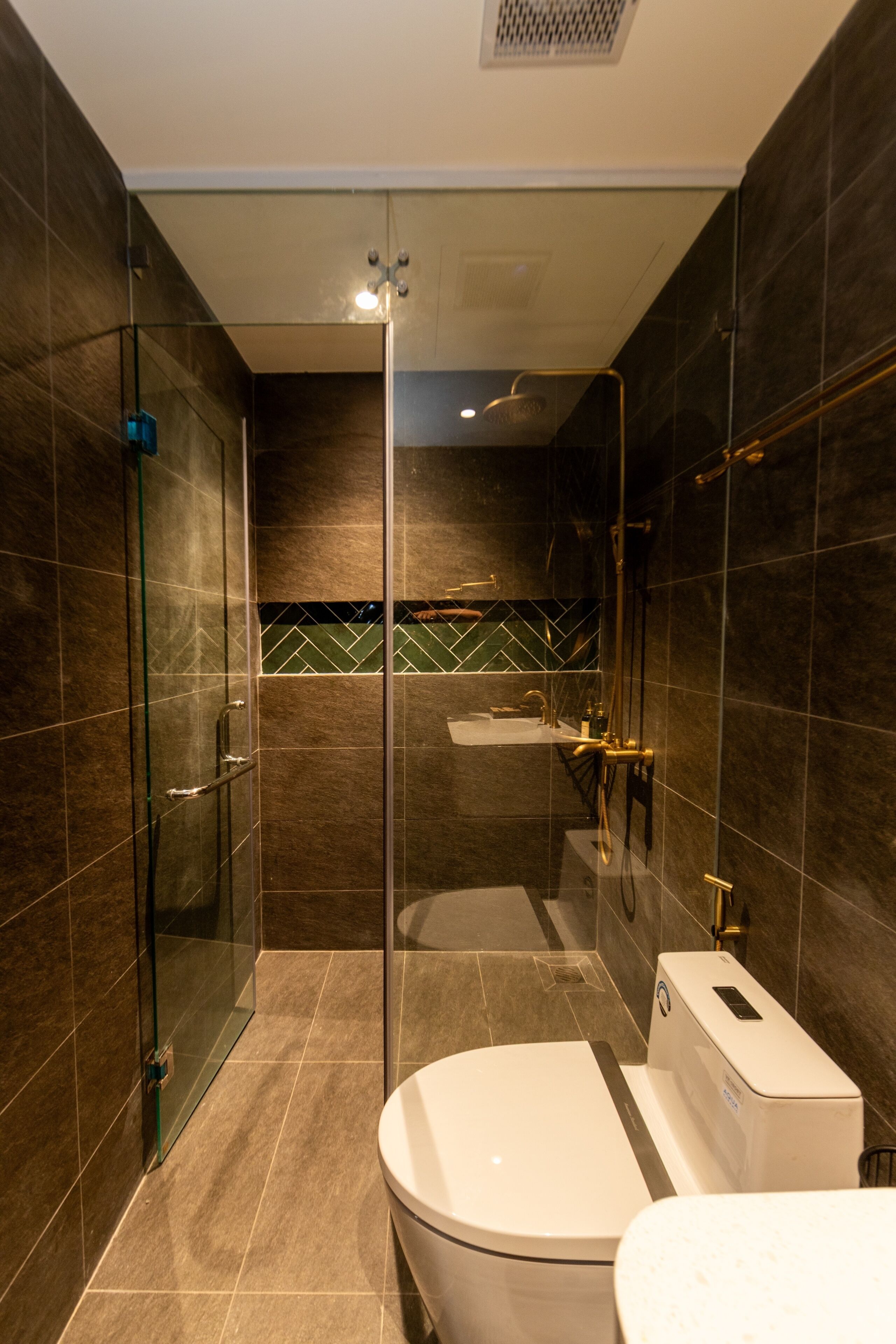 Une salle de bain moderne dotée d’une douche à parois de verre, de toilettes et d’un lavabo.