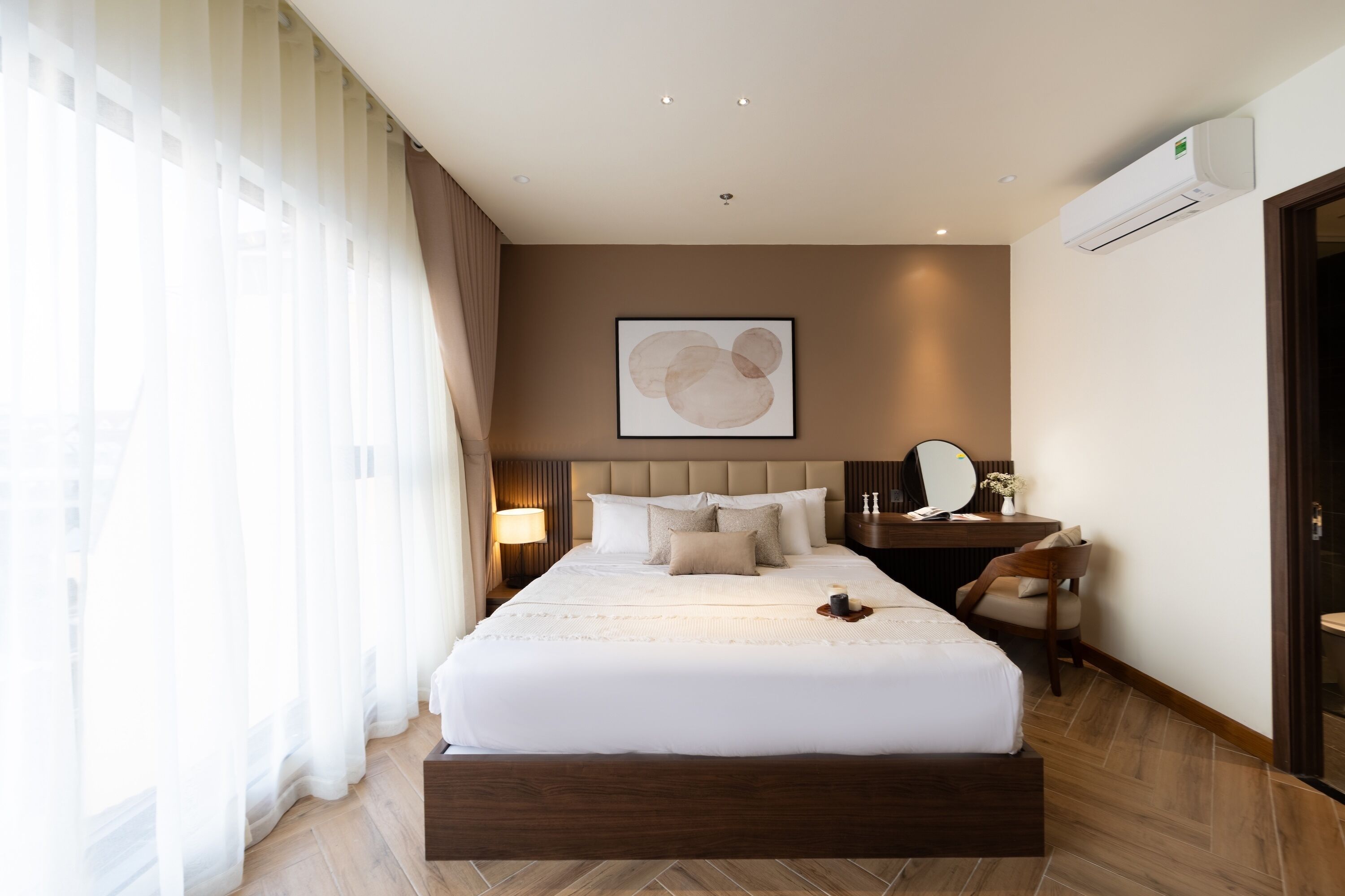 Una camera d'albergo con un letto grande, un comodino con una lampada, uno specchio e un condizionatore d'aria a muro.