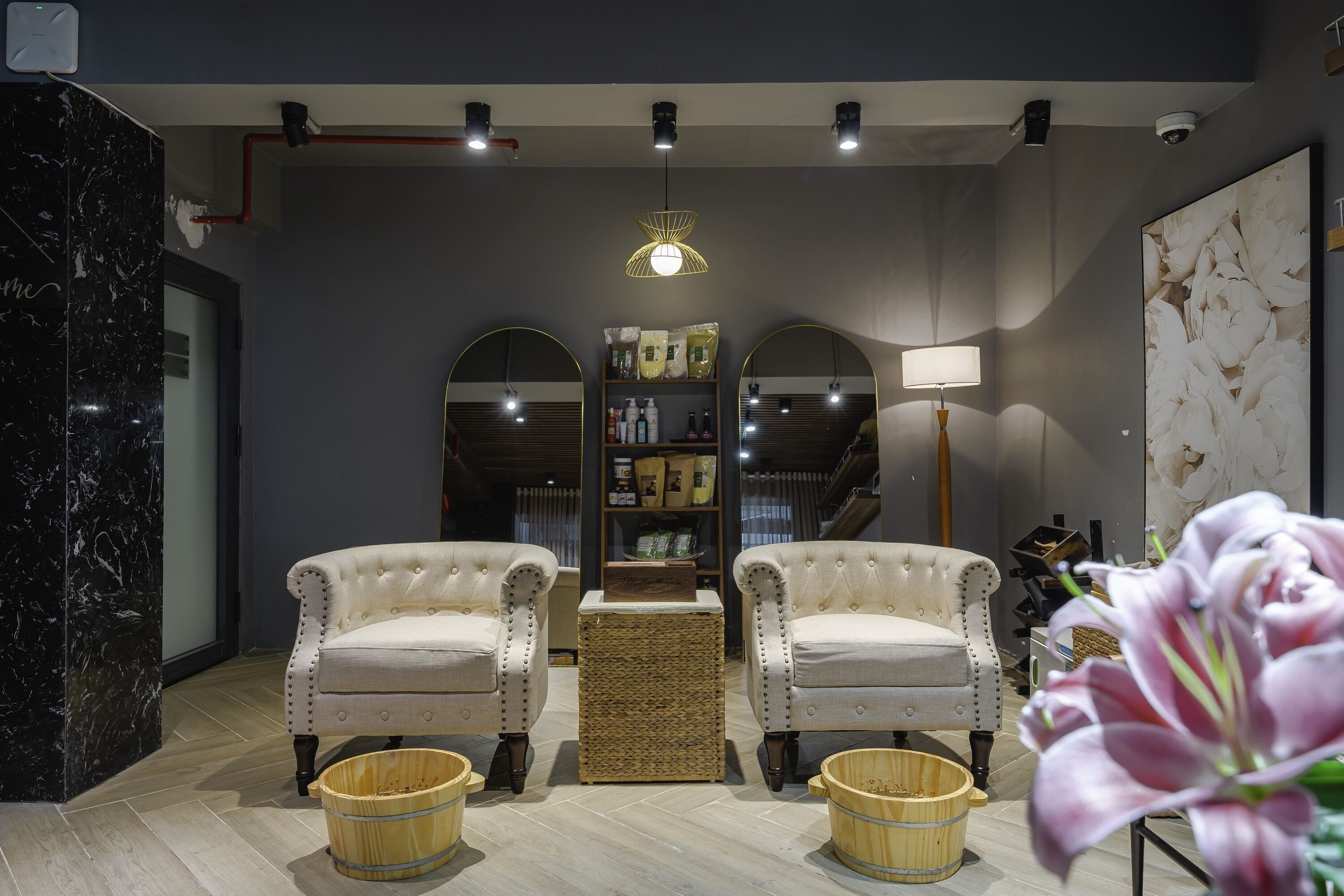 A modern interior with two tufted armchairs, a central woven table, and a mirrored wall.